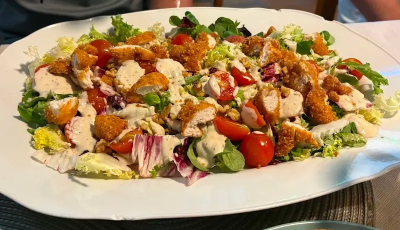 Ensalada de pollo crujiente con tomates cherry, nueces y salsa blanca en fuente grande