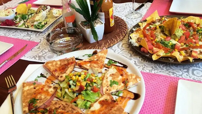 Quesadillas con ensalada de maíz y una fuente de nachos sobre manteles rosas
