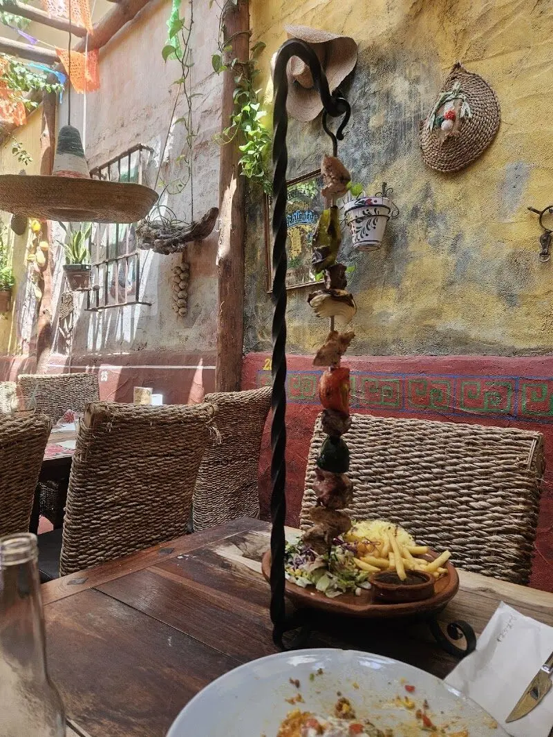 Brocheta colgante de carne y verduras con patatas fritas en el patio de decoración mexicana