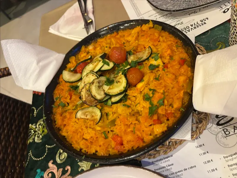 Paella de verduras con calabacín y tomates cherry en paellera, sobre la carta de mantel