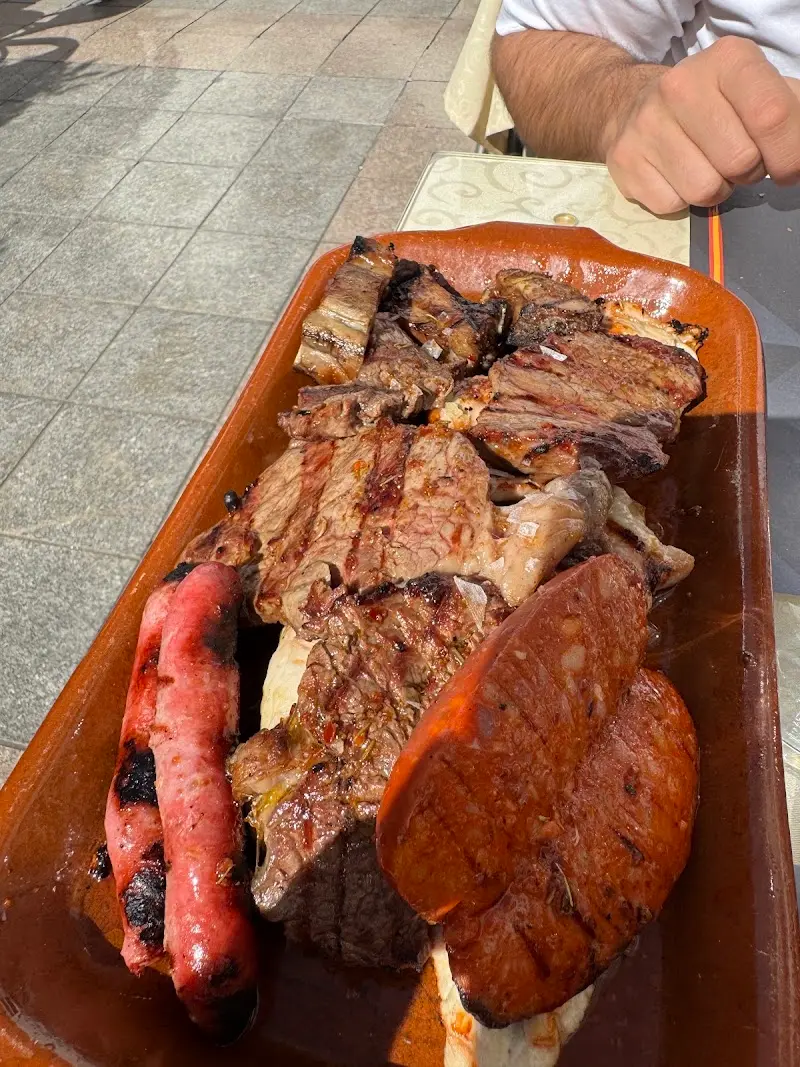 Parrillada de carnes con chorizo y morcilla en fuente de barro en la terraza