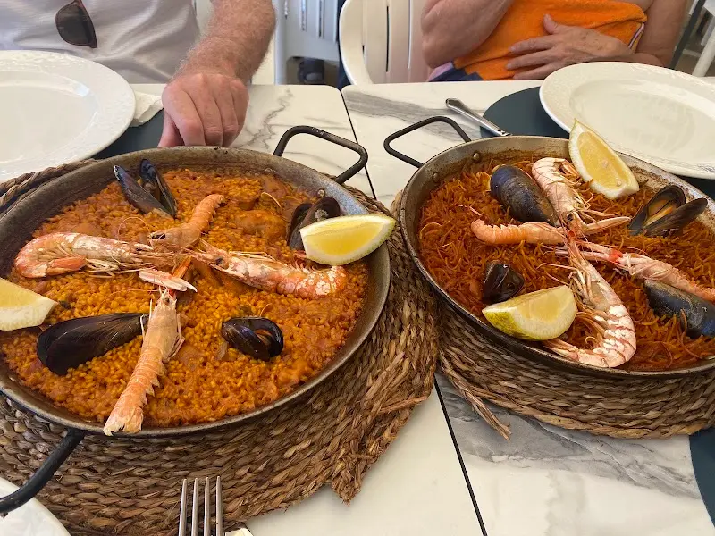 Paella de marisco y fideuá en sus paelleras con cigalas, mejillones y limón