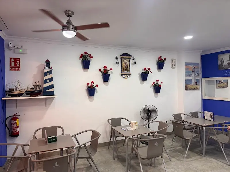 Comedor con macetas azules con geranios, faro decorativo y barcos de maqueta en la pared