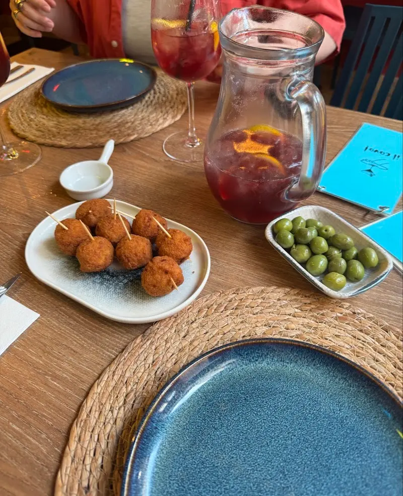 Croquetas con palillos, aceitunas verdes y una jarra de sangría sobre la mesa