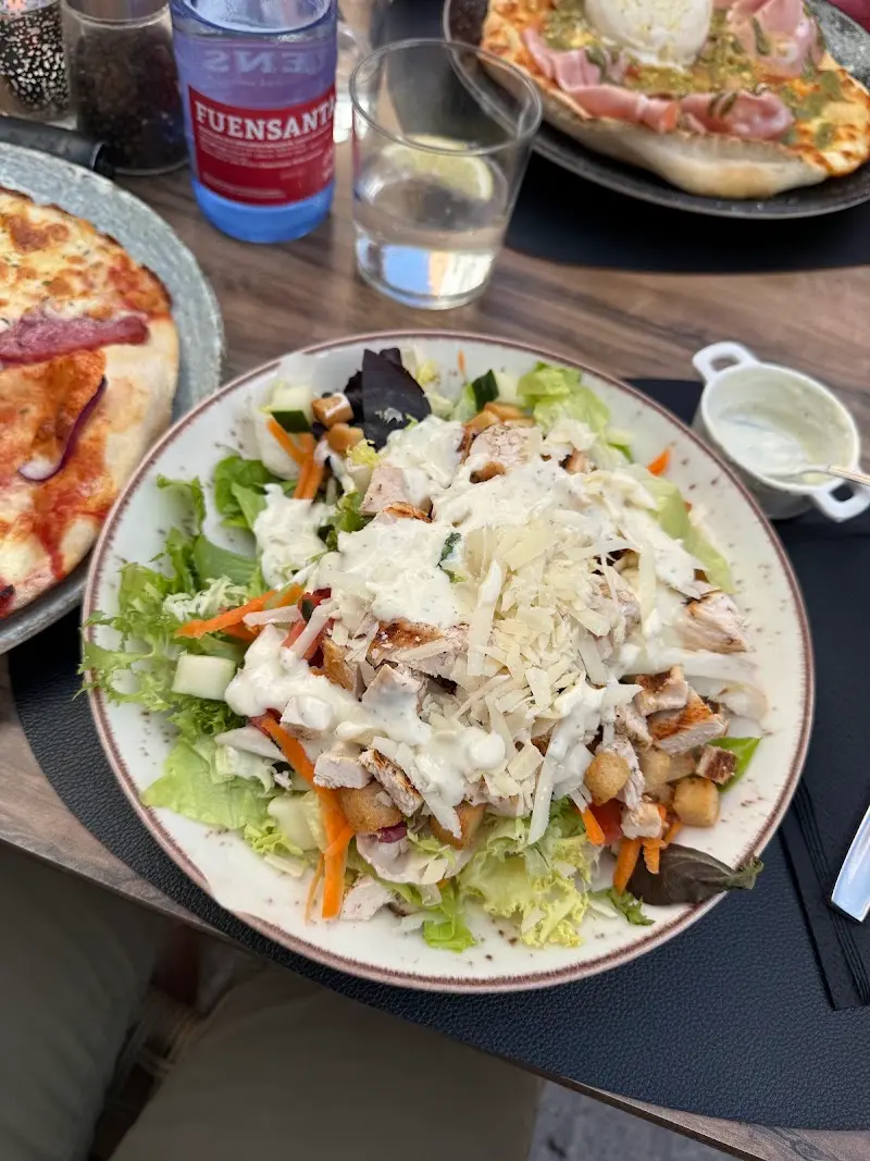 Ensalada César con pollo, parmesano y picatostes junto a dos pizzas