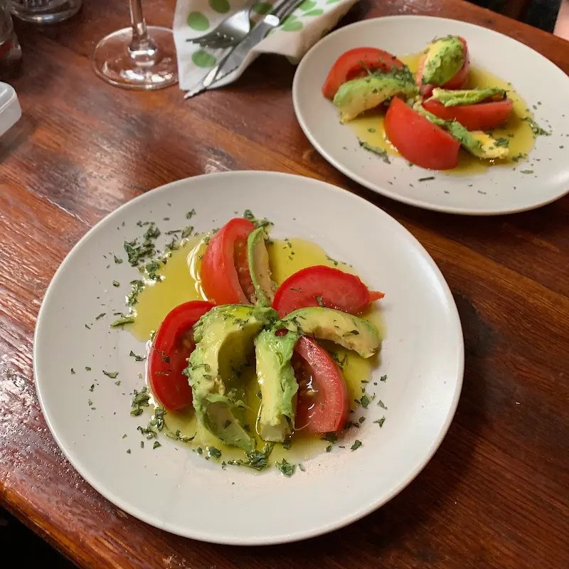 Ensalada de tomate y aguacate con aceite de oliva y hierbas sobre mesa de madera
