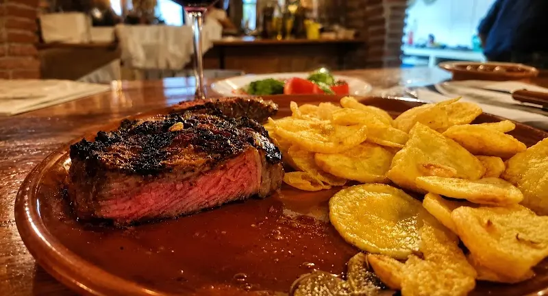 Entrecot a la brasa poco hecho con patatas fritas caseras en plato de barro