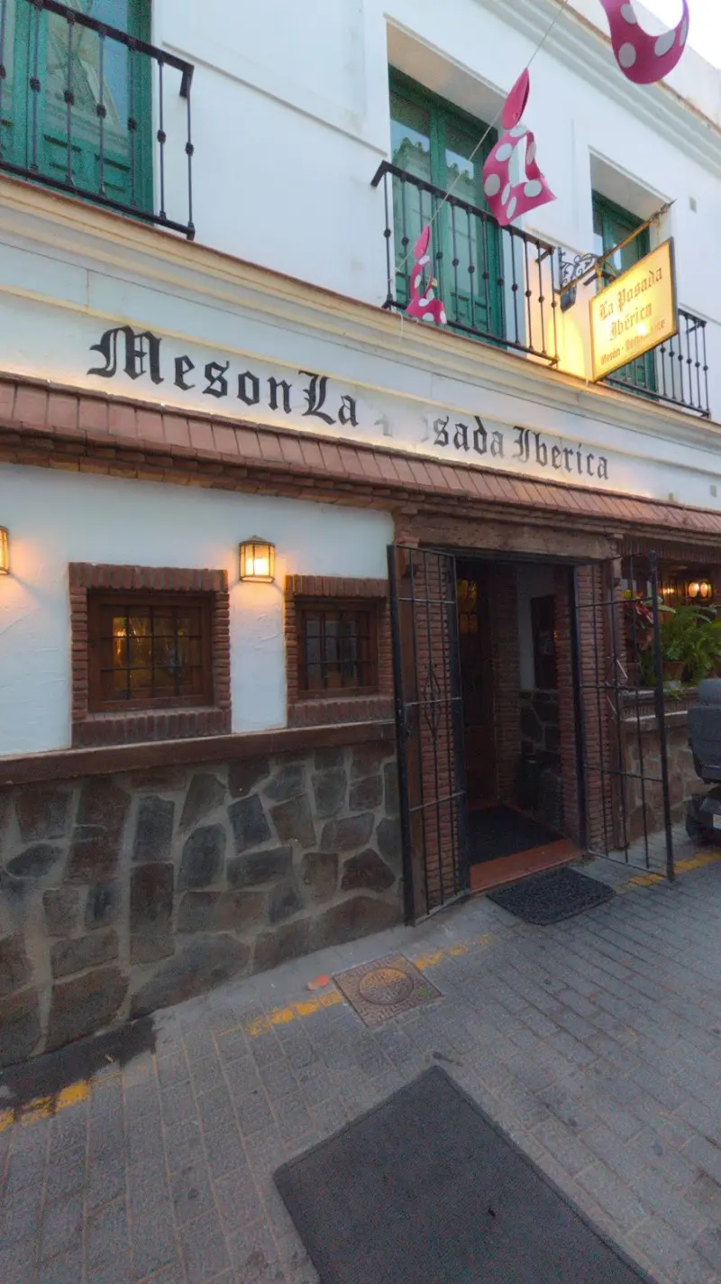Entrada del mesón con banderines de lunares y faroles encendidos al anochecer