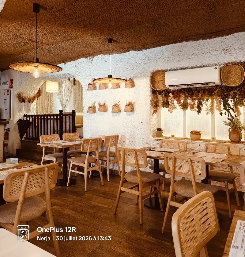 Comedor con sillas de rejilla, paredes encaladas, lámparas de fibra y flores secas