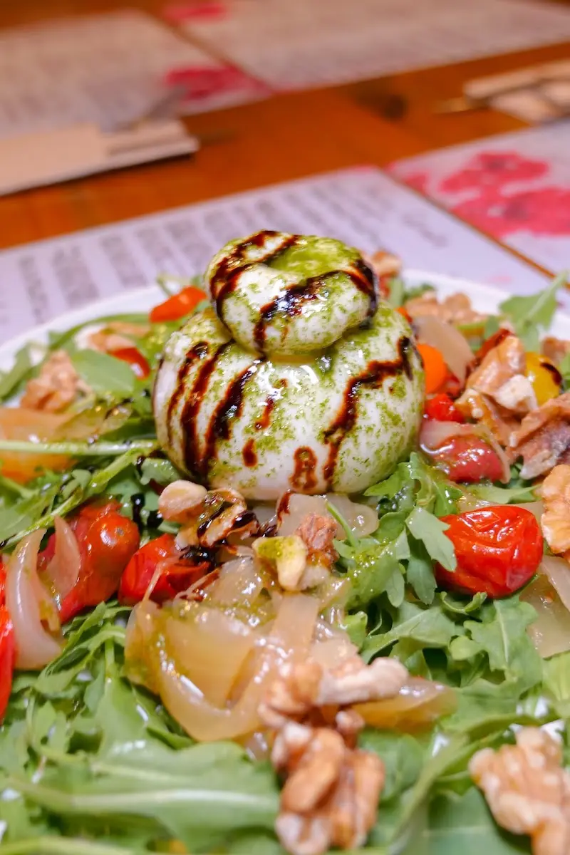 Burrata con pesto y reducción de balsámico sobre rúcula, tomates asados y nueces