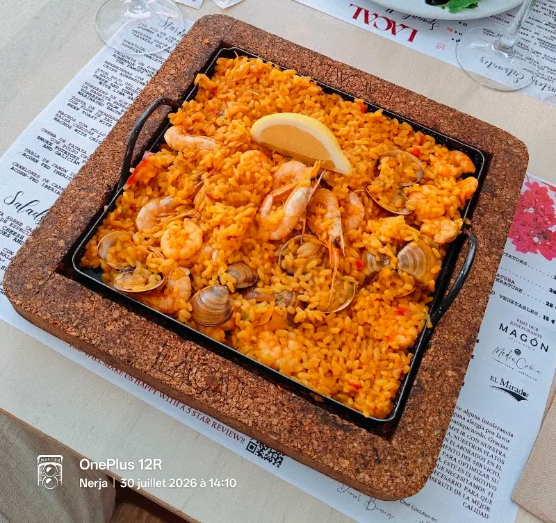Paella de marisco con gambas, almejas y limón servida en paellera sobre la mesa de Lacal