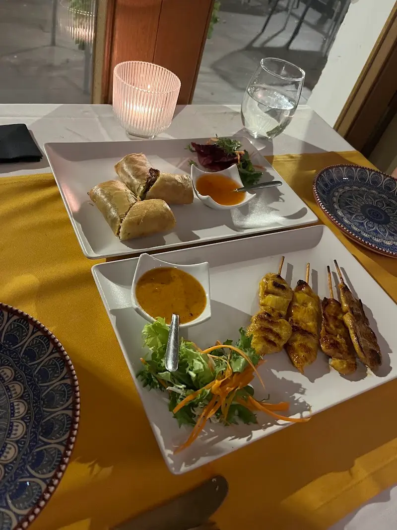 Brochetas de pollo satay con salsa de cacahuete y rollitos de primavera a la luz de una vela