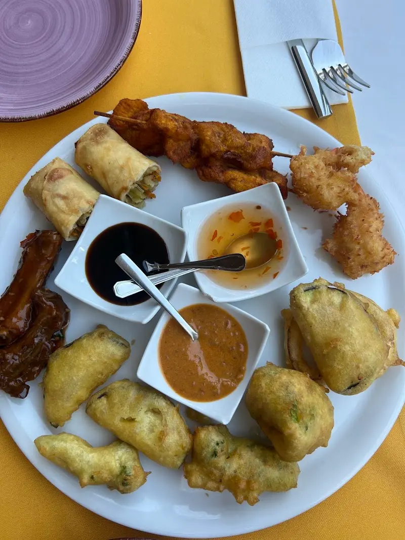 Surtido de entrantes tailandeses fritos con brochetas, rollitos y tres salsas en Lan Sang