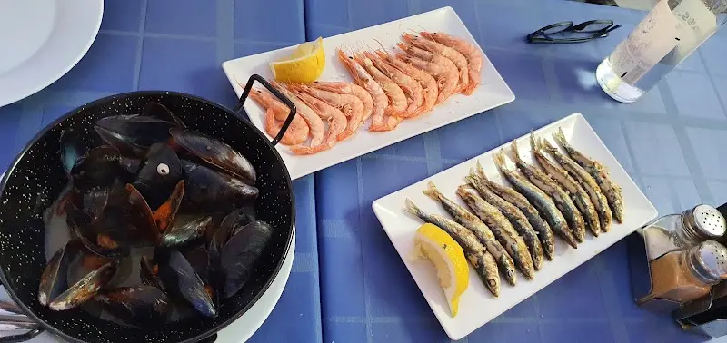 Mejillones al vapor, gambas a la plancha y pescaditos con limón sobre mantel azul