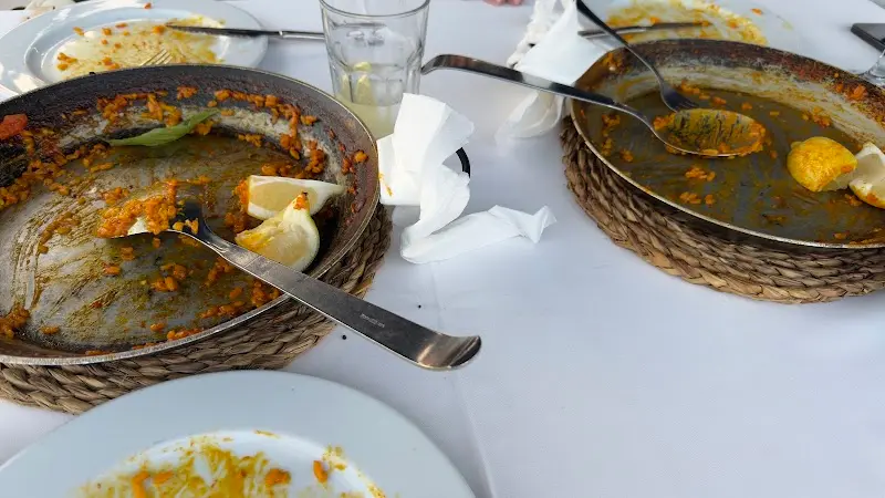 Dos paelleras casi vacías con rodajas de limón sobre la mesa tras la comida