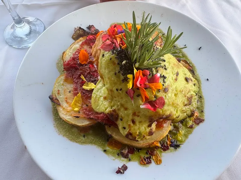 Plato de verduras asadas con salsa verde, romero y flores comestibles