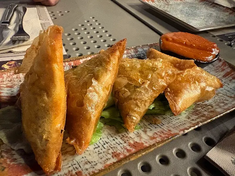 Briouats de pasta filo fritos sobre lechuga, con salsa roja para mojar
