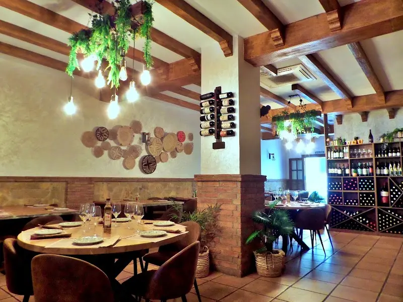 Comedor con mesas redondas, techo de vigas, botellero de pared y plantas colgantes