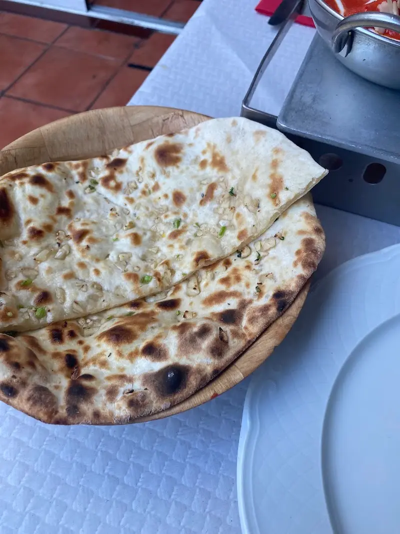 Pan naan de ajo en una fuente de madera sobre mantel blanco