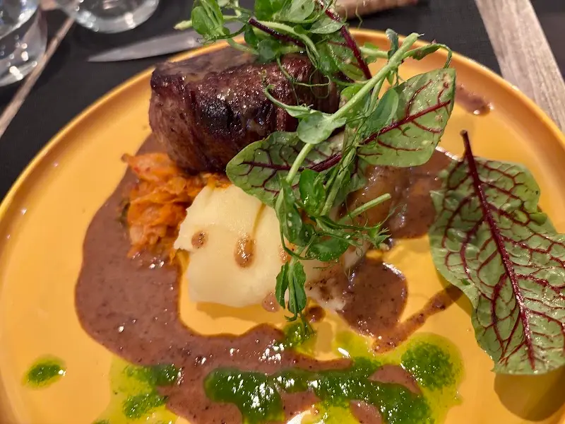 Carne guisada con puré de patata, salsa oscura y brotes verdes en Numa