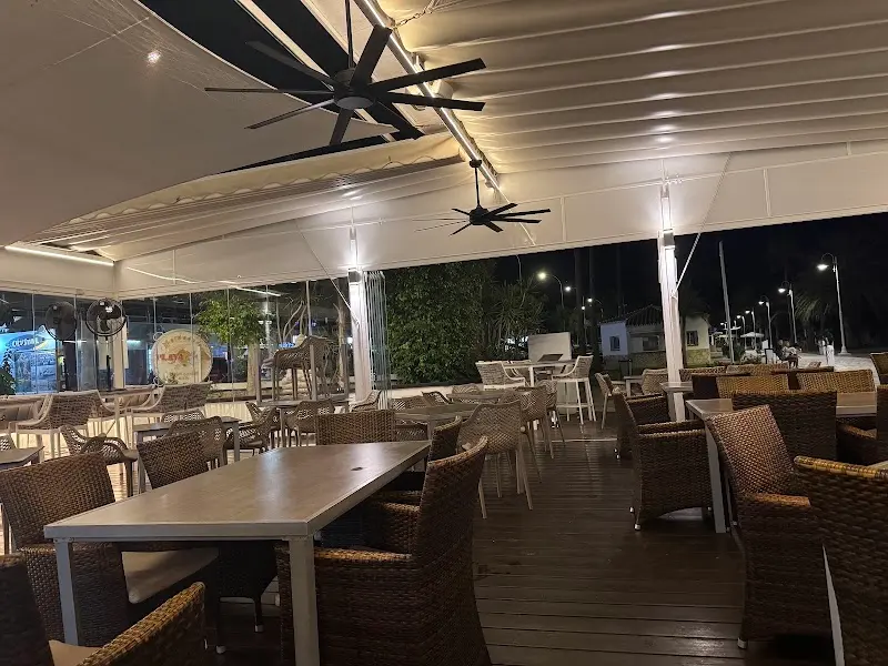 Terraza cubierta y vacía de noche, con ventiladores de techo y sillas de mimbre