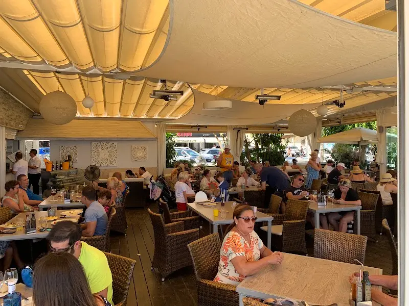 Comedor bajo toldos lleno de comensales a mediodía, con lámparas de papel