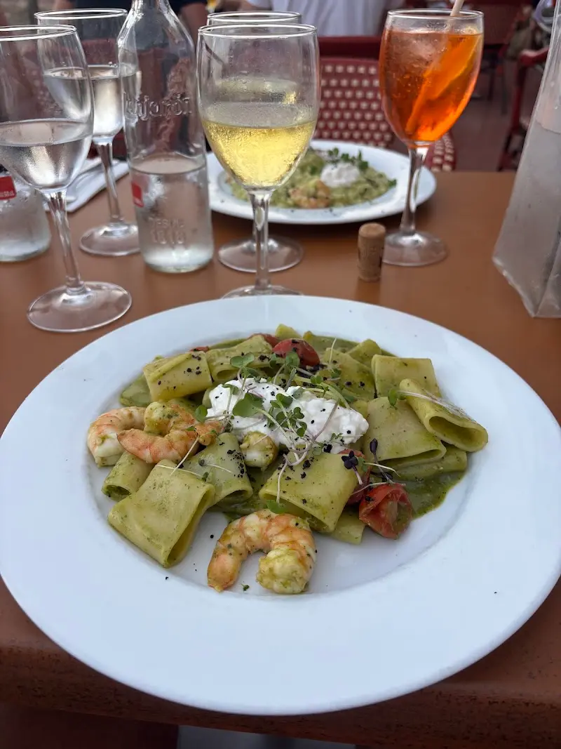 Paccheri al pesto con langostinos y burrata, con copas de vino y un spritz