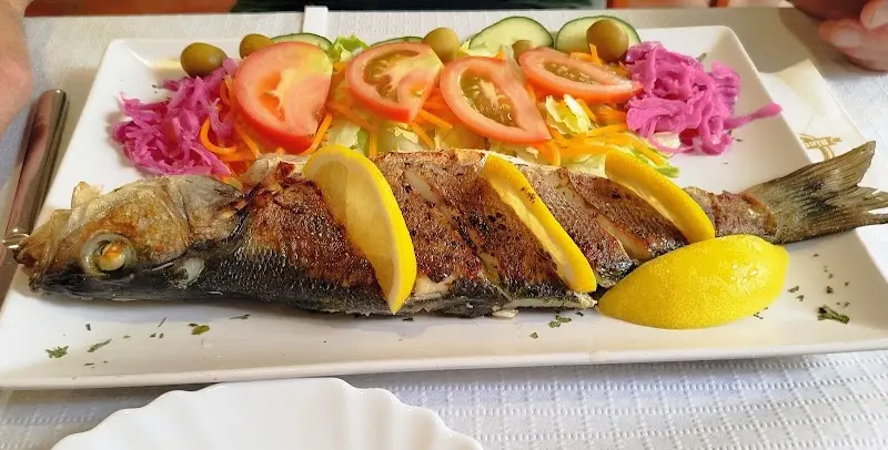 Pescado entero a la plancha con rodajas de limón y ensalada de tomate y col