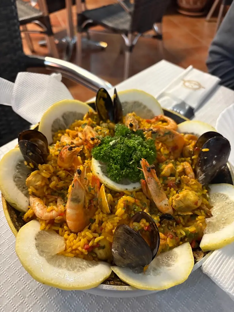 Paella de marisco con gambas, mejillones y rodajas de limón en la paellera