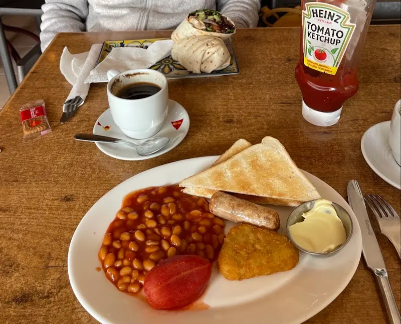 Desayuno inglés con alubias, salchicha, tostadas, rösti de patata, tomate y café
