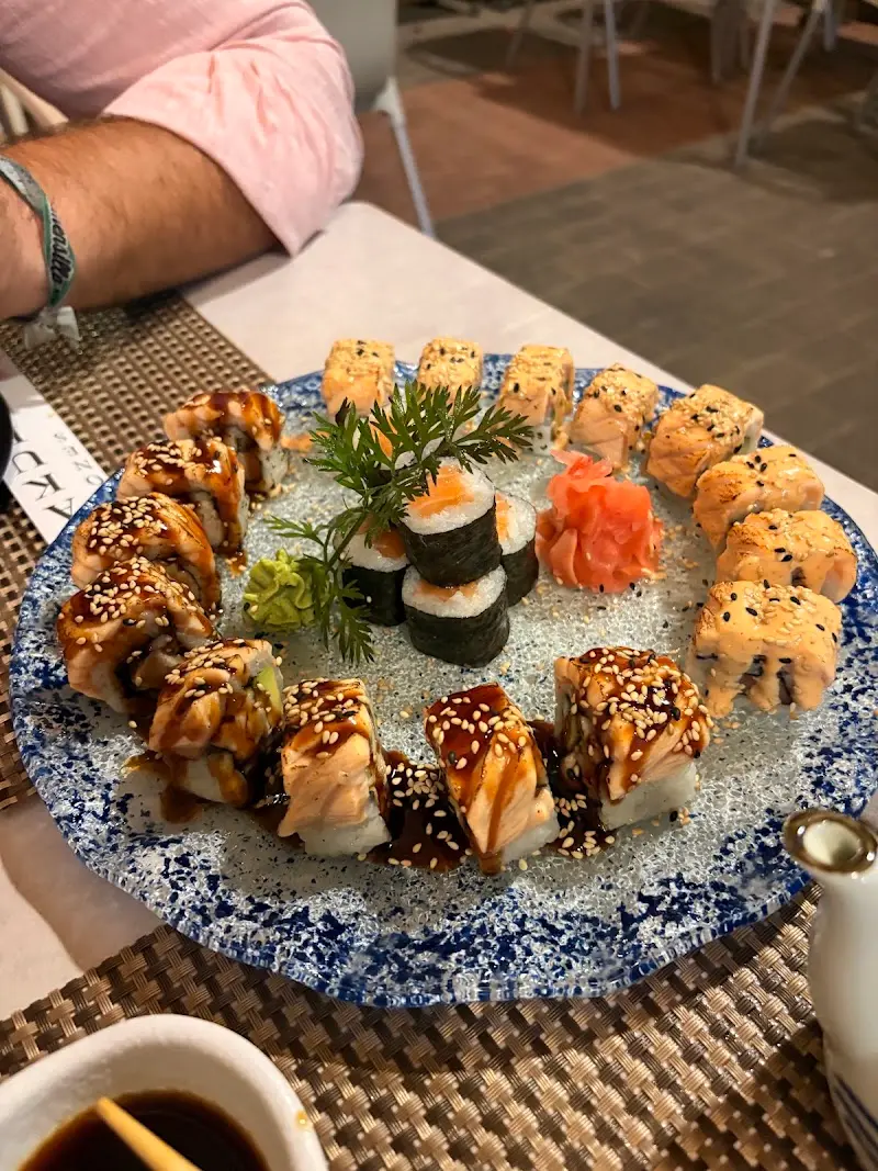 Fuente de sushi variado con rolls flambeados de salmón, makis, jengibre y wasabi en Sakura