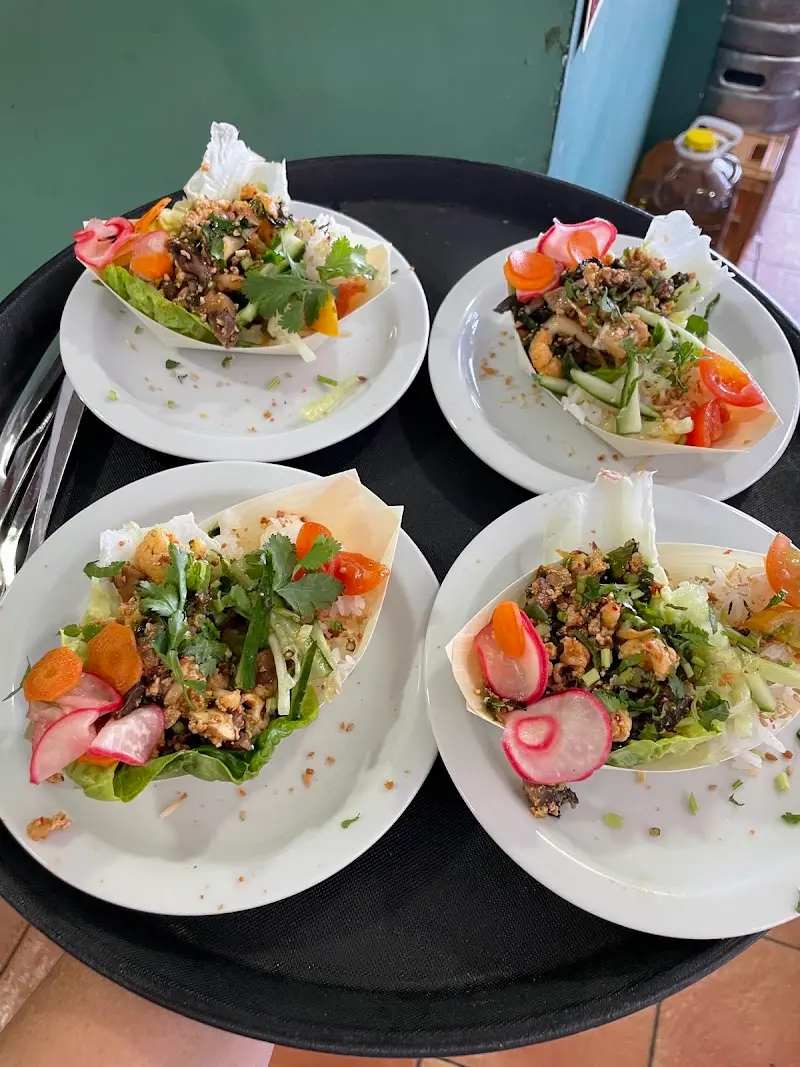 Cuatro platos de wraps de lechuga con carne picada, rábano, zanahoria y cilantro en una bandeja