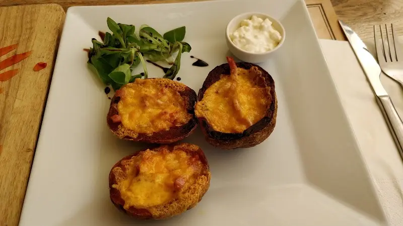 Pieles de patata gratinadas con queso y beicon, con canónigos y salsa de queso