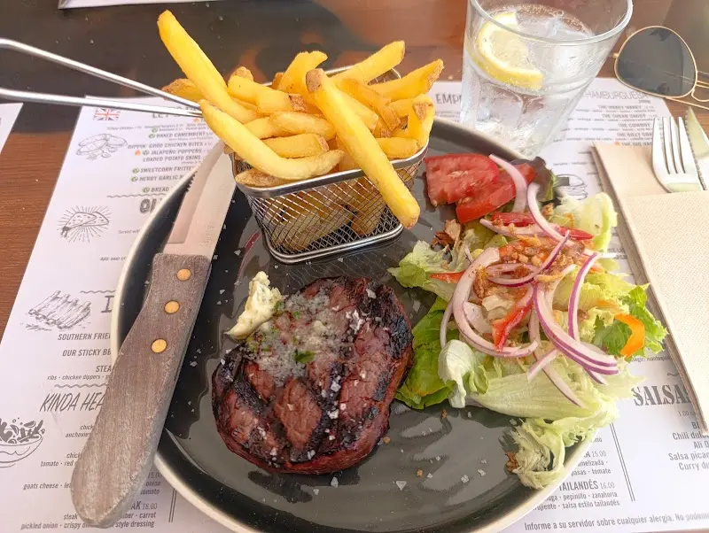 Filete a la parrilla con mantequilla, patatas fritas en cesta y ensalada mixta