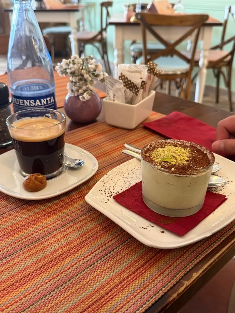 Café solo con amaretti y un vaso de tiramisú de pistacho sobre mantel de rayas
