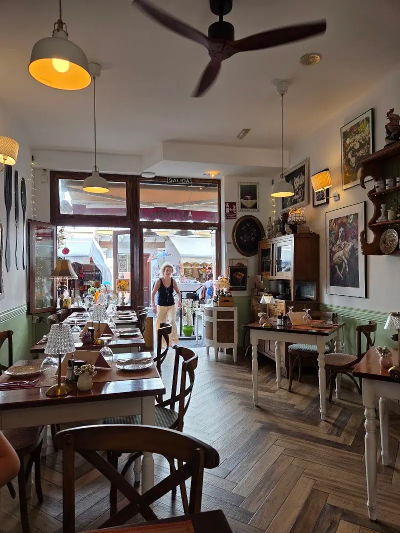 Comedor de la trattoria con lámparas colgantes, cuadros y suelo de madera en espiga
