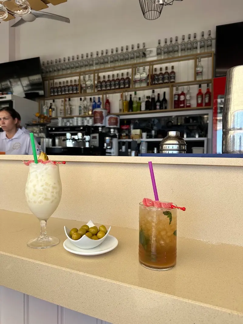 Piña colada y cóctel con hierbabuena junto a un platito de aceitunas en la barra