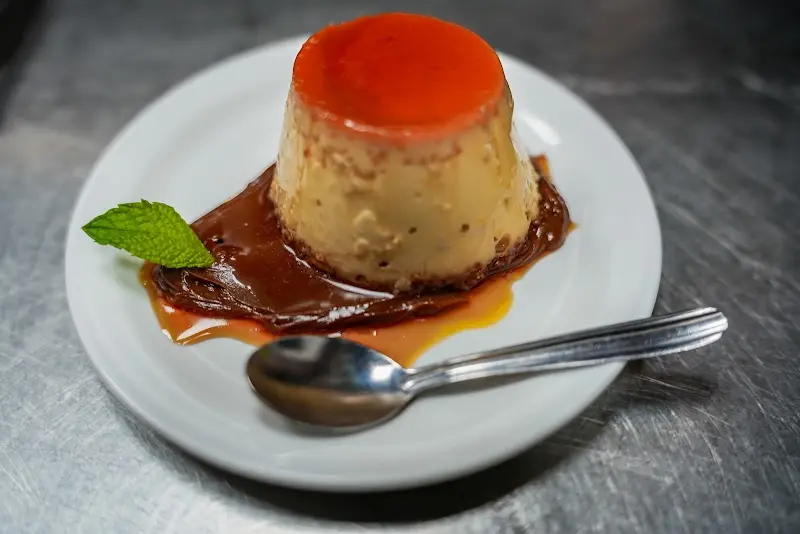 Flan con caramelo y hoja de hierbabuena en un plato con cucharilla
