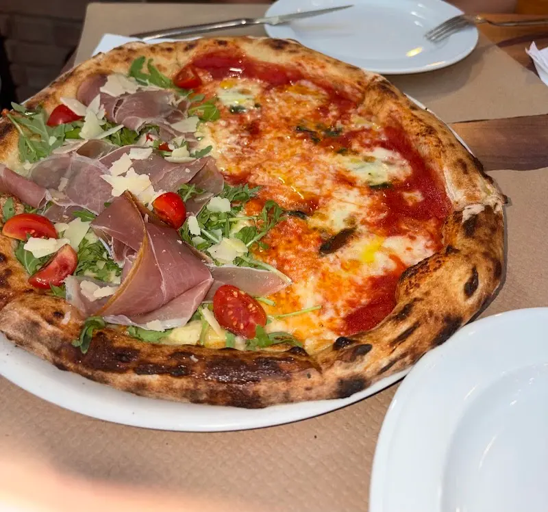 Pizza mitad con jamón curado, rúcula y tomate cherry, mitad margarita