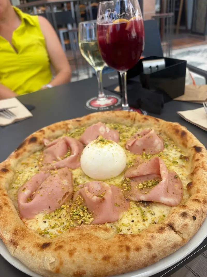 Pizza blanca con mortadela, burrata y pistacho junto a una copa de sangría en Roots