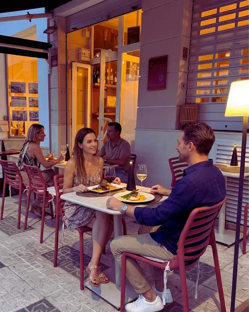 Clientes cenando al anochecer en la terraza de Safran, con pescado y verduras en los platos