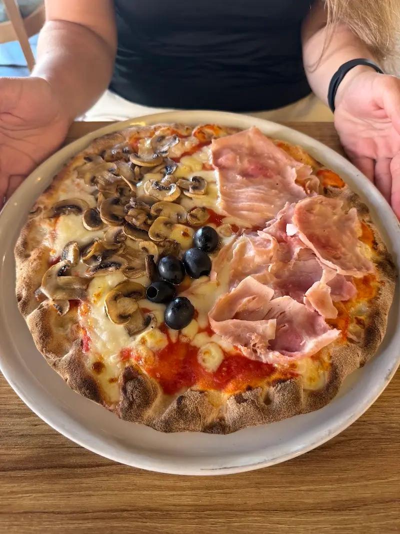 Pizza con champiñones, jamón cocido y aceitunas negras sobre una mesa de madera