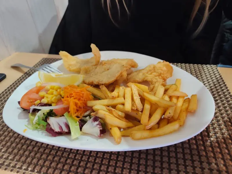 Plato de pescado rebozado con patatas fritas, limón y ensalada