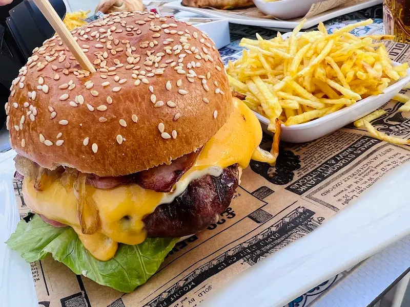 Hamburguesa con queso fundido, beicon y cebolla, acompañada de patatas fritas