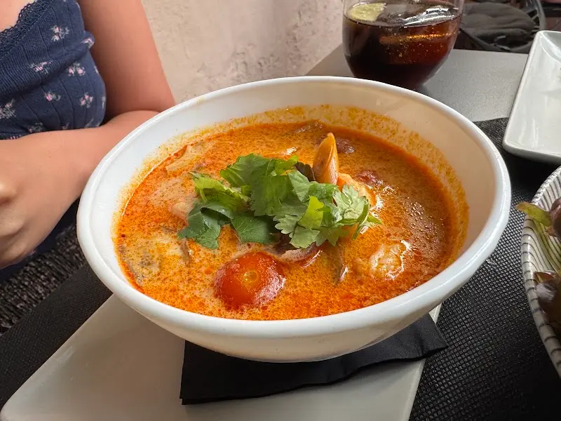 Cuenco de sopa picante con gambas, tomate cherry y cilantro fresco en SomSom