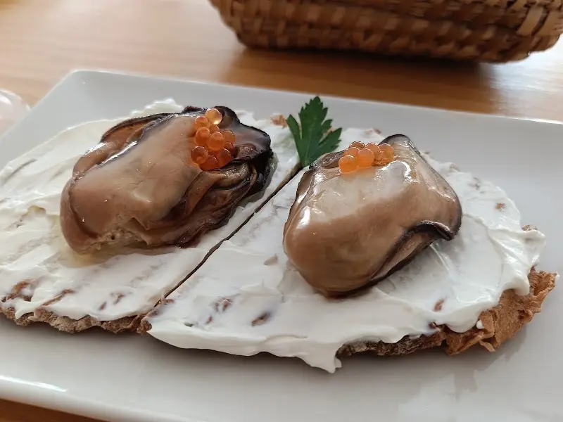 Tosta con queso crema coronada con moluscos y huevas de pescado