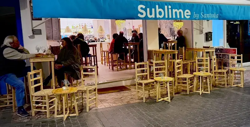 Terraza de Sublime by Santoña de noche, con sillas de enea y clientes junto al local abierto