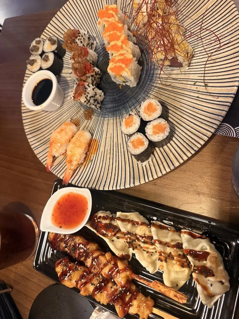 Plato de rayas con makis, uramakis y nigiris de langostino, junto a gyozas y brochetas con salsa