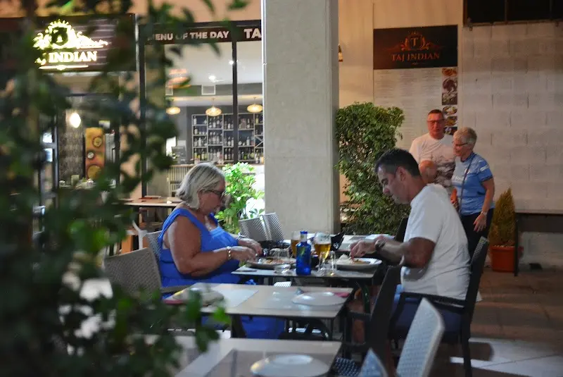 Clientes cenando en la terraza junto a la entrada iluminada del restaurante