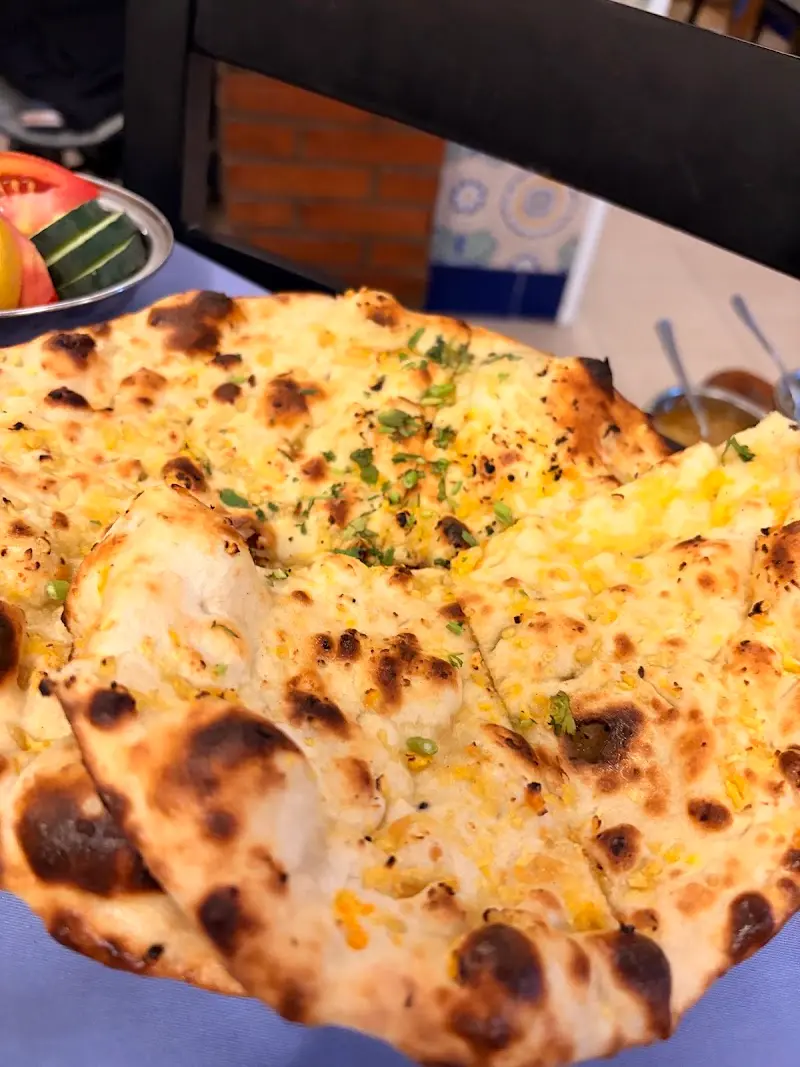 Pan naan con ajo y hierbas cortado en porciones sobre la mesa